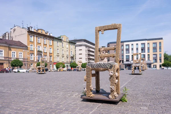KRAKOW, POLAND - JUNE, 2017: Massive chair on cobblestone street in art installation in memory of Jewish ghetto. Krakow with popul. of 800,000 people has 2.35 mill. foreign tourists annually — Stock Photo, Image