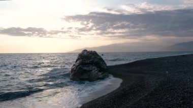 Dalgalar deniz sahil şeridi ile büyük Rock, günbatımında haddelenmiş görünümünü