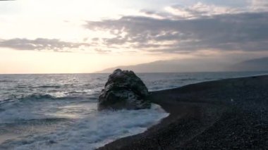 Dalgalar deniz sahil şeridi ile büyük Rock, günbatımında haddelenmiş görünümünü