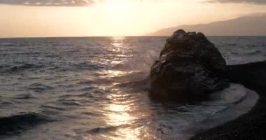 Dalgalar deniz sahil şeridi ile büyük Rock, günbatımında haddelenmiş görünümünü