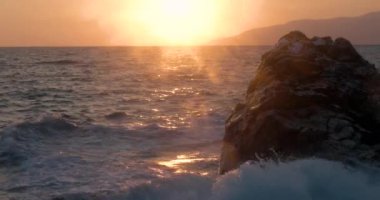 Dalgalar deniz sahil şeridi ile büyük Rock, günbatımında haddelenmiş görünümünü