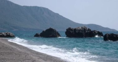 Dalgalar deniz sahil şeridi ile büyük kayalar, haddelenmiş görünümünü