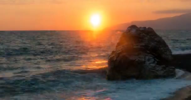 Vista de las olas rodadas en la línea de la costa del mar con enorme roca al atardecer Time Lapse con zoom — Vídeos de Stock