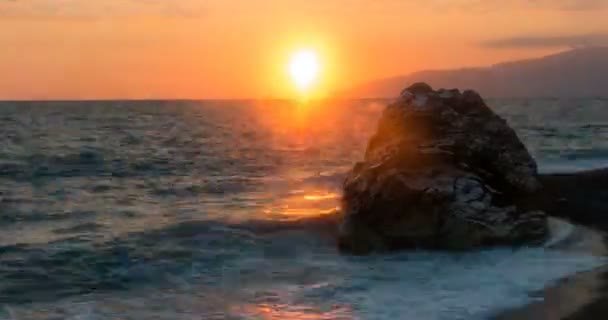 Vista de las olas rodadas en la línea de la costa del mar con enorme roca al atardecer Time Lapse con zoom — Vídeo de stock