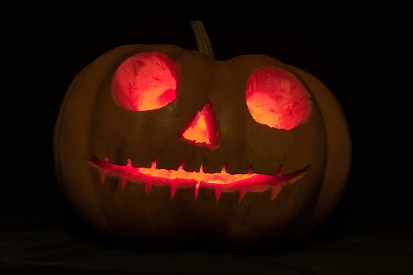 Halloween-Kürbisse mit gruseligem Gesicht und brennender Kerze auf schwarzem Grund — Stockfoto