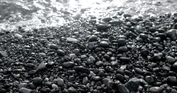 Wellen wälzen sich auf einer Kieselküste mit glitzernder und schimmernder Meeresoberfläche — Stockvideo