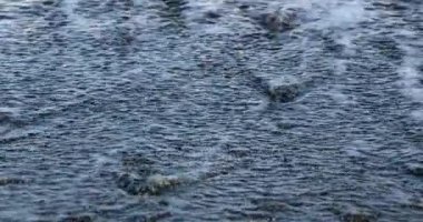 Parlak ve deniz yüzeyi parıldayan bir çakıl taşı sahil şeridi üzerinde inişli çıkışlı dalgalar
