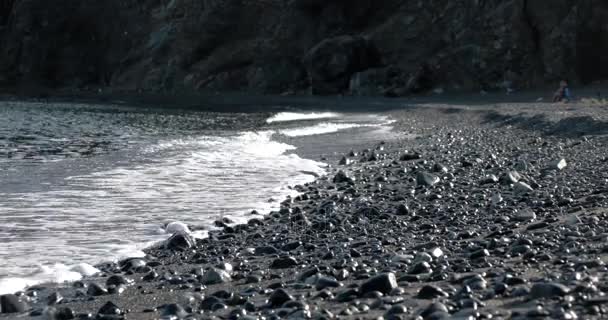 Ondas rodando en una línea costera de guijarros con superficie de mar brillante y brillante — Vídeos de Stock