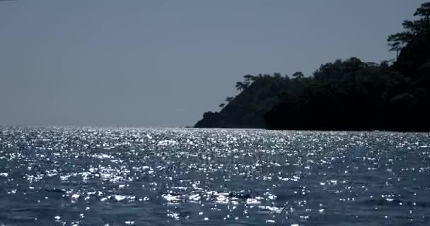 Sparkling Wavy Sea Water está brilhando em um dia ensolarado de verão com silhueta da ilha — Vídeo de Stock