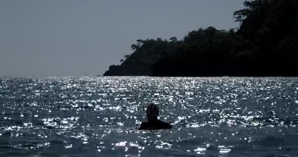 섬 배경 석양에 빛나는 물결 바다에서 남자의 실루엣 — 비디오