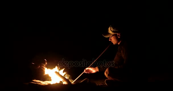 Mann sitzt nachts am Lagerfeuer — Stockvideo