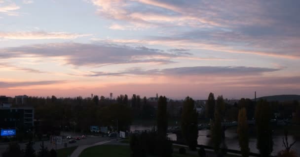 Puesta de sol sobre el río de la ciudad pequeña y un puente sobre él, transición del tráfico del coche del día a la noche (lapso de tiempo / Timelapse ) — Vídeos de Stock