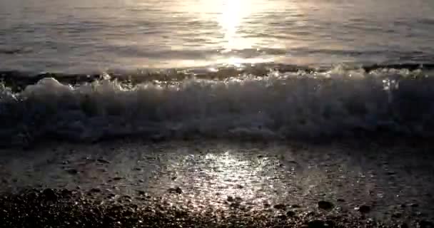 Onde Rolling in su una linea di ciottoli costa al sorgere del sole con ascolto e scintillante superficie del mare — Video Stock