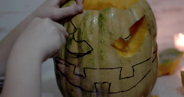 Chica talla detalles de un Jack o 'Lantern en naranja calabaza de Halloween con una herramienta de talla — Vídeo de stock