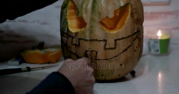 Girl Carves Details of a Jack o 'Lantern on Orange Halloween Pumpkin using a Carving Tool — стоковое видео