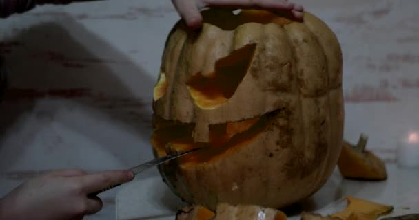 Ragazza intagli dettagli di un Jack o 'Lanterna sulla zucca arancione di Halloween utilizzando uno strumento di intaglio — Video Stock