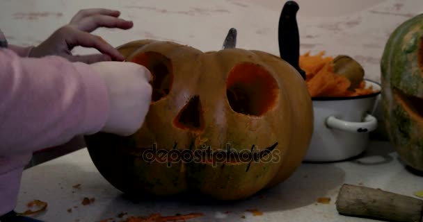 Girl Carves Details of a Jack o 'Lantern on Orange Halloween Pumpkin using a Carving Tool — стоковое видео