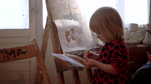 Egy aranyos kis lány festés Gouache színű, a fehér papírlap — Stock videók