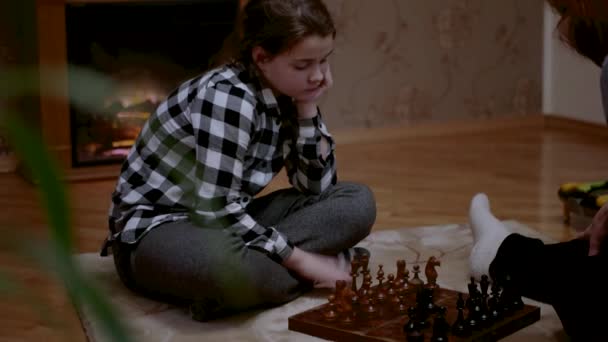 Kleines Mädchen beim Schachspielen zu Hause auf dem Holzschachbrett — Stockvideo
