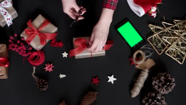 トップ ビュー女性クリスマス プレゼントをラッピング、ショッピングのためのタッチ スクリーンのスマート フォン タブレットを使用して — ストック動画