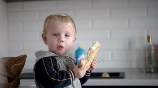 Pequeño chico divertido comiendo pan con cara feliz — Vídeo de stock