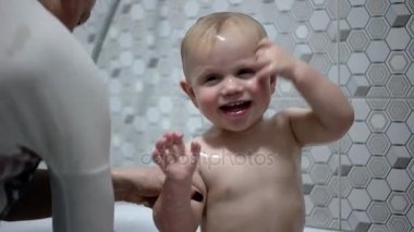 Anne bebeği şampuan ile bir kabarcık banyo yıkama. Mutlu zaman O'nun anne dökülen su onun kafasına çocuktur