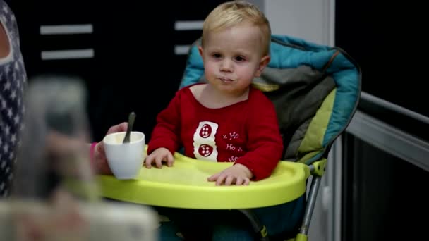 Anya etetés neki a kisfiú, egy kanál. Anyja ad ételt imádnivaló két éves gyermeke — Stock videók