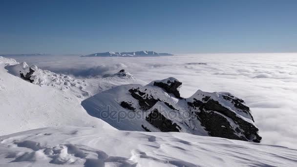 Zeitraffer-Aufnahme von Wolken unter dem Berggipfel im Winter bei sonnigem Tag — Stockvideo