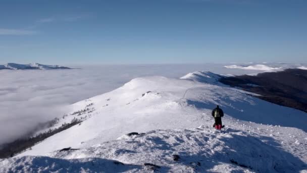 Viaggiatori con gli zaini fanno un'escursione invernale sopra le nuvole con una vista sulle cime lontane da una costa del mare nuvoloso — Video Stock