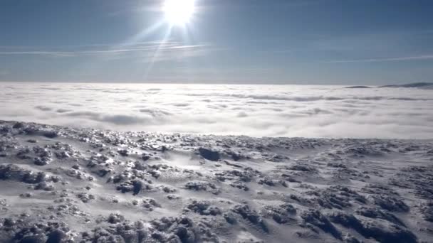 Viajantes com mochilas fazem uma caminhada de inverno acima das nuvens com vista para os picos distantes por uma costa do mar da nuvem — Vídeo de Stock