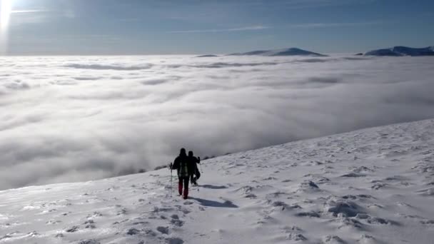 Travellers With Backpacks Make a Winter Hike Above the Clouds With a View of the Distant Peaks by a Coast of the Cloud Sea — Stock Video