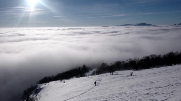 Seyahat sırt çantaları ile bulut deniz kıyısında tarafından uzak tepeleri manzaralı bulutların üzerinde bir kış yürüyüş yapmak — Stok video