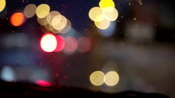 Conduire la nuit. Vue sur le pare-brise et les voitures floues dans la ville. Vue floue et pluvieuse depuis la fenêtre de la voiture — Video