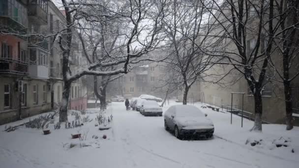 Schneefall liegt im Hof des Schlafquartiers, bedeckt von schneebedeckten Fahrzeugen — Stockvideo