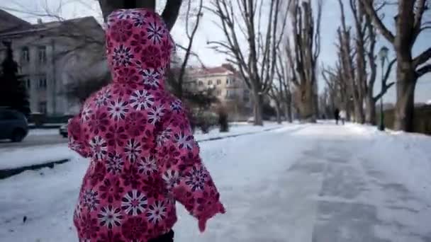 3 year old Funny Girl Having Fun and Running by Snow-Covered Embankment Alley in Winter. Steadicam Shot — стоковое видео