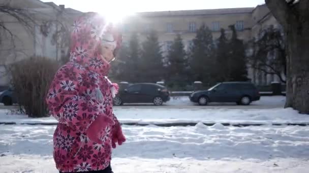 3 岁滑稽的女孩开心和运行由冰雪覆盖的路堤小巷里的冬天。斯坦尼康来拍摄镜头 — 图库视频影像
