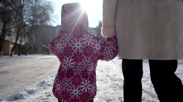 겨울에 눈 덮인 제방 골목에 의해 그녀의 어머니와 함께 산책 하는 3 년 된 소녀. Steadicam 샷 — 비디오