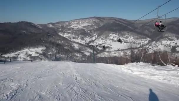 Le skieur rapide descend les pentes enneigées par une journée immaculée sur la montagne avec un ciel clair et des arbres enneigés sur le côté — Video