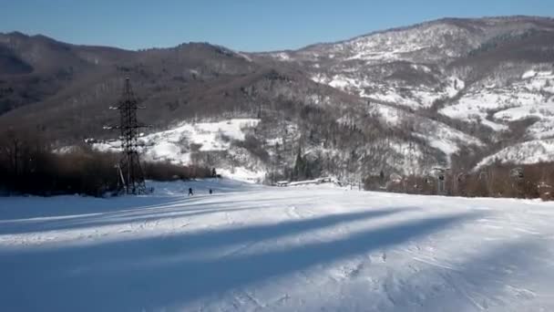 Rychlé lyžař jede po zasněžených svazích na nedotčené den na horách s jasnou oblohou a zasněžené stromy na straně — Stock video