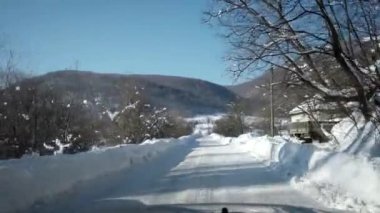Kışın kırsal ülke yolda arabayı. Kar ve buz karayolu üzerinde ve dağlar ve tepeler yakın. Birinci şahıs bakış açısı ön cam ile.