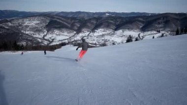 Ağır çekim arkadan görünüş karlı yamaç aşağı profesyonel kayakçı oymacılık