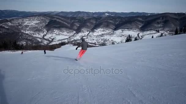 Slow Motion Rear View of the Skier caring down the snow slope — стоковое видео