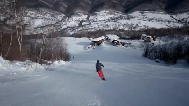 Pohled zezadu na vyřezávání profesionální lyžař po zasněženém svahu — Stock video