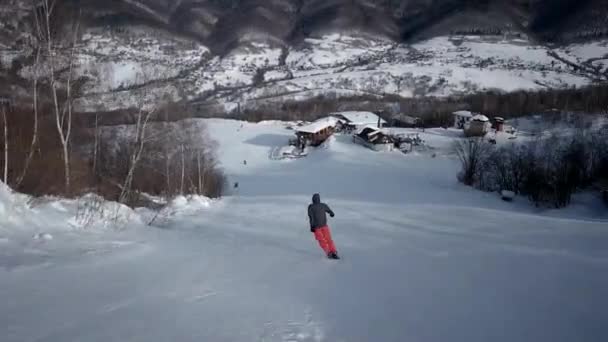 Vue arrière du skieur professionnel qui descend la pente enneigée — Video