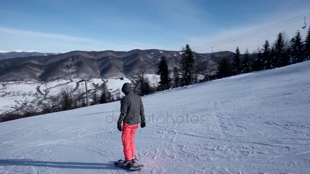 Zeitlupe Rückansicht eines professionellen Skifahrers beim Carven den schneebedeckten Hang hinunter — Stockvideo