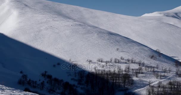 Панорамування Панорама порошок покриті гору з лижних трас в снігу ліс сільської місцевості в сонячний день зими — стокове відео