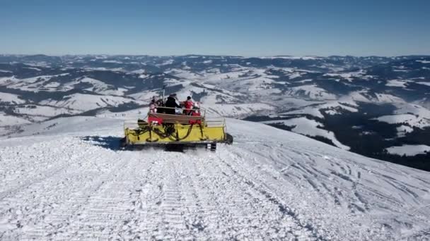Skiërs rijden op de rug van een Snowcat op een sneeuw bedekt berg op een zonnige winterdag — Stockvideo