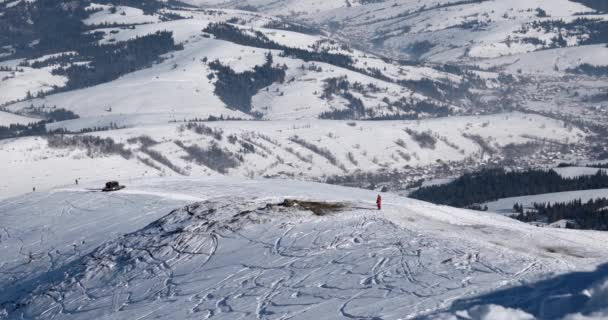 Gatto delle nevi con gli sciatori sul retro Cavalcando su una collina innevata in una giornata di sole invernale — Video Stock