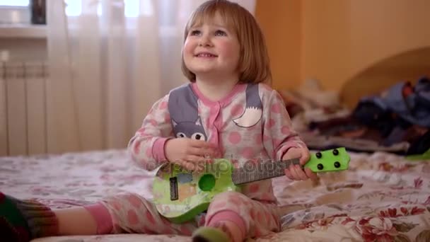 Cute Little Girl gry jej gitarze i śpiewa piosenki w sypialni — Wideo stockowe