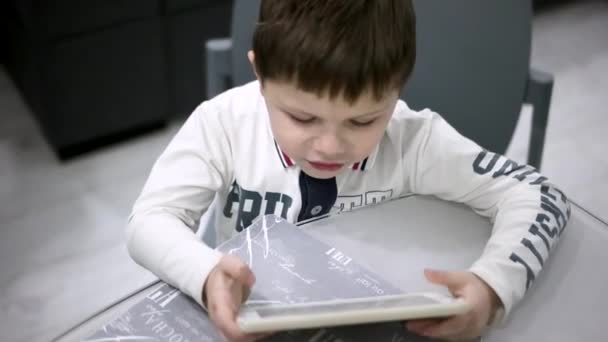Menino jovem absorvido em jogar jogos em seu tablet digital em casa — Vídeo de Stock